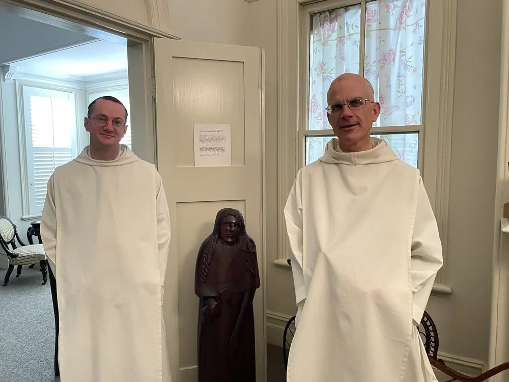 Fr Prior and Br Gregory stand next to life size statue of the Venerable who, due to a broken spine when she was young, remained of small size until her death at the age of 28.